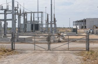 Closed gates at an electrical substation beside a partially built data center site in Texas.