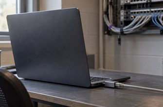 Laptop connected through an Ethernet adapter on a desk, with network equipment in the background.