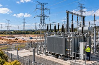Editorial illustration of high-voltage electricity infrastructure and a planned AI data center development, representing grid delays affecting the Microsoft Nscale project.